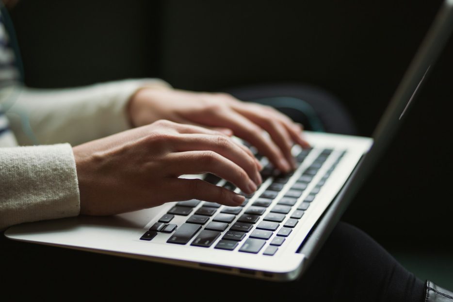 Women's hands typing on a laptop's keyboard